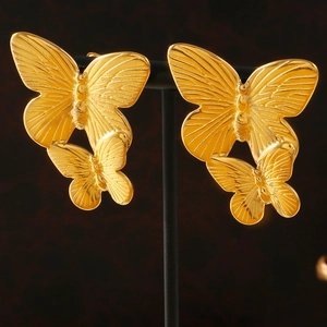 Elegant gold double-layered butterfly stud earrings on professional black display stand