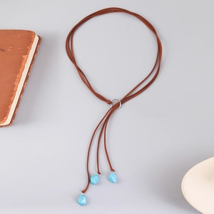 Detail of bohemian lariat necklace with brown suede cord and turquoise stone pendants