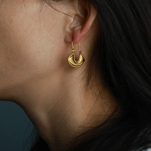 Polished gold U-shaped hoop earrings with milgrain edge detail on female model