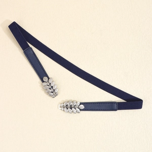 Detail of navy elastic belt featuring silver leaf-shaped interlocking metal buckle closure