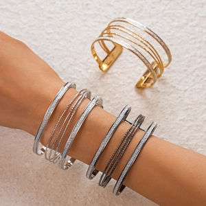 Macro detail of multilayer geometric open bangles with gold, silver and gun black finish