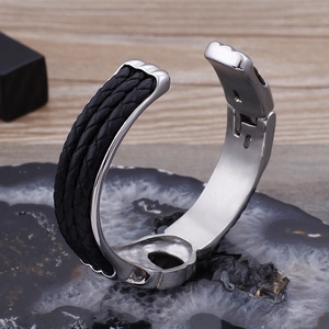 Détail macro du cuir tressé incrusté sur le bracelet rigide en acier argenté pour homme