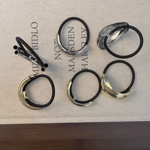 Detail of minimalist gold and silver metal hair ties on textured fabric background