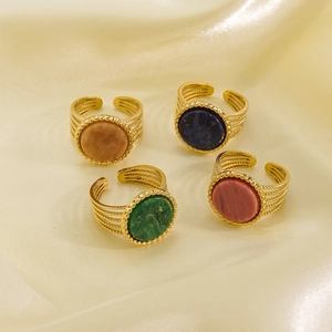 Detail of four 14K gold-plated rings with colorful stones on beige silk fabric