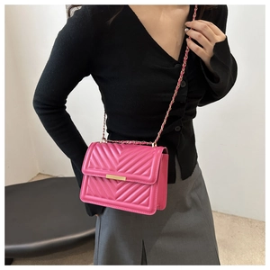 Detailed close-up of pink quilted crossbody bag with gold chain and metal bar buckle lock