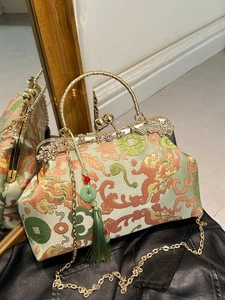 Retro embroidered handbag with dragon motifs, metal frame and jade tassel on black surface