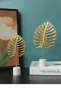 Close-up of golden metal monstera leaf ornaments with marble base for modern home decor
