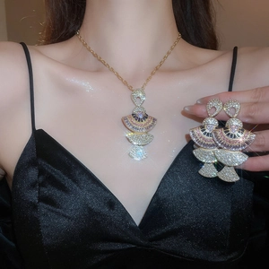 Macro shot of gold fan-shaped necklace and earring set with pink crystals on a model