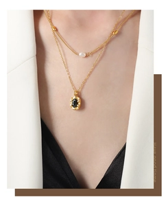 Close-up of double layer 18k gold chain with freshwater pearl and black oval pendant
