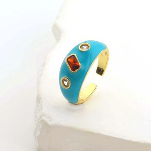 Dettaglio macro dell'anello in smalto turchese con zircone rosso e bordi dorati lucidi