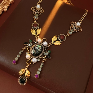 Détail du collier vintage doré avec perles et pierres colorées sur fond de cuir