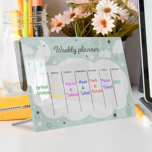Close-up of acrylic weekly planner showing colorful handwritten meal prep notes on desk