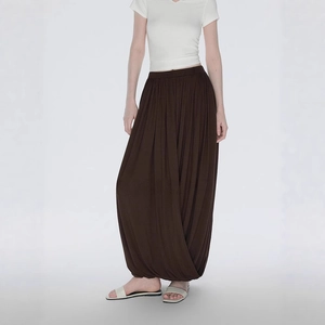 Detail view of deep brown asymmetrical loose skirt pants showing fabric drape and texture