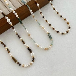 Detailed macro of vintage style pearl and gemstone necklaces on a dark wood stand