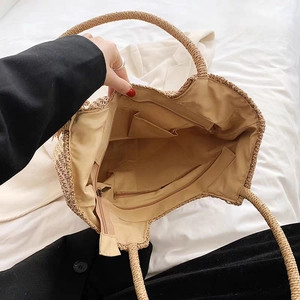 Interior detail of khaki woven straw tote bag showing zipper pocket and spacious lining