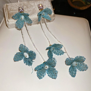 Detailed close-up of long floral tassel earrings with blue fabric and purple crystals