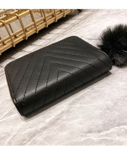 Detail of black quilted faux leather purse with matching plush pompom keychain