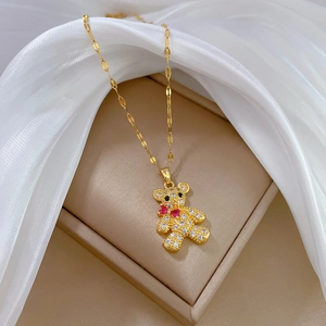 Titanium steel bear necklace with crystals on a golden chain over silk fabric