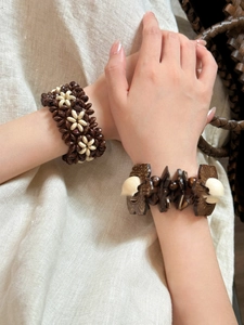 Detail of bohemian coconut shell and wood bead stretch bracelets on a linen background