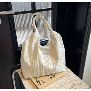 Detailaufnahme einer weißen Tasche mit Faltenstruktur und eingenähtem KISS YOURSELF Etikett