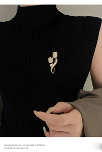 Detail of gold tulip brooch with pearls and crystals pinned on a black garment