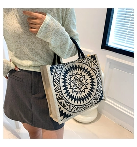 Detailed view of large linen tote bag with geometric sun pattern held by a model