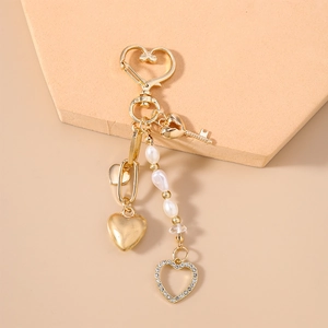 Detail of gold keychain with heart and key charms featuring pearls and clear beads