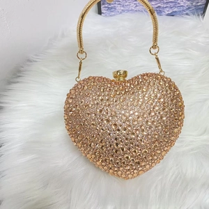 Macro view of champagne rhinestone heart evening bag with textured gold handle
