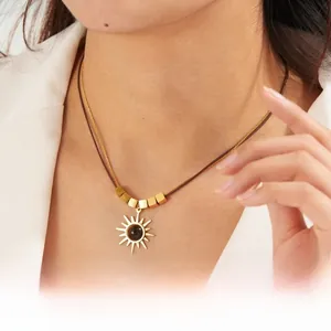 Detail of a vintage gold sun pendant necklace with brown beads on a brown cord