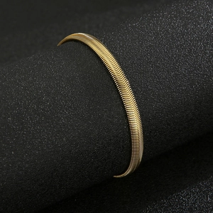 Detailed close-up of flat gold snake chain with reflective wavy woven texture