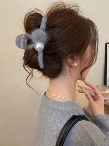 Detail of gray plush hair claw clip with large pearl on model elegant winter hairstyle