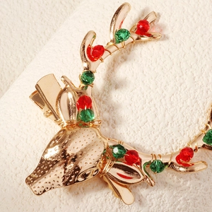 Detail shot of Christmas reindeer hair clip with red and green crystal beads on gold alloy