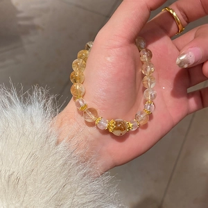 Detail of yellow crystal beaded bracelet with zircon flower charm on a wrist