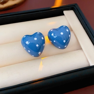 Detail of blue heart-shaped earrings with white polka dots in a jewelry box storage slot