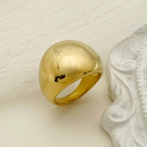 Polished gold-plated chunky dome ring shown from side view on aesthetic textured background