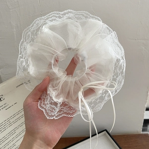 Detailed shot of white organza scrunchie with lace trim and delicate ribbon bow accessory