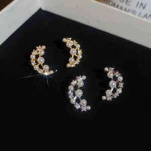 Macro detail of crescent moon earrings with inlaid pearls and sparkling cubic zirconia
