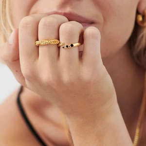 Detail of gold-plated rope texture and open rings with black stones on model fingers