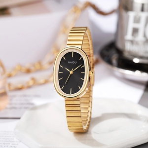Detail of elegant gold oval watch with black dial and metal chain strap on a white stand