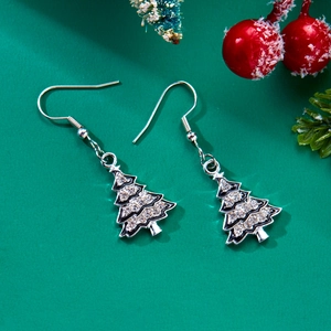 Detailed view of silver Christmas tree earrings with rhinestones on festive background