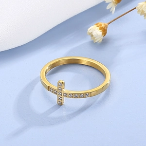 Detail shot of a gold hollow cross ring with sparkling cubic zirconia on a blue background