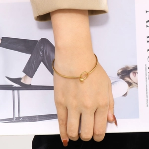 Minimalist gold stainless steel open bangle with bead detail worn by a model