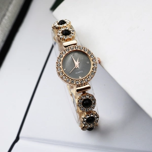 Close-up of golden jewelry watch with black chalcedony links and crystal accents