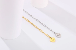 Detail view of gold and silver heart pendants with Love engraving on paperclip chains