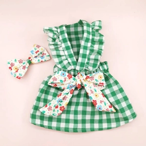 Detailed view of green plaid dog dress with floral bow accessory and fabric texture