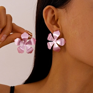 Detail of pink matte metallic flower earrings worn by a model in a minimalist style
