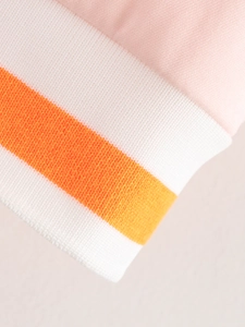 Detail of pink jacket with orange and white striped ribbed knit cuffs and collar