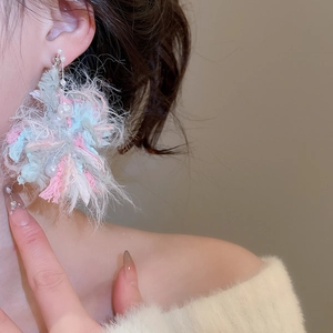 Detail of wool flower pearl earrings showing fluffy texture and mixed colors on model