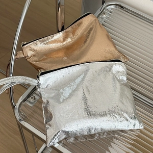Detail of metallic snakeskin texture on gold and silver cosmetic bags with black zippers