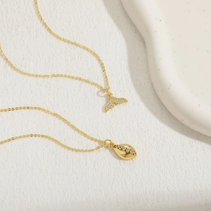 Detail shot of 14K gold plated fish tail and shell pendants with zircon stones